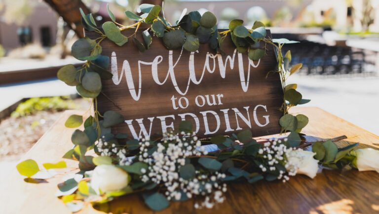 Rustic wooden "Welcome to our Wedding" sign decorated with eucalyptus garland and baby's breath flowers